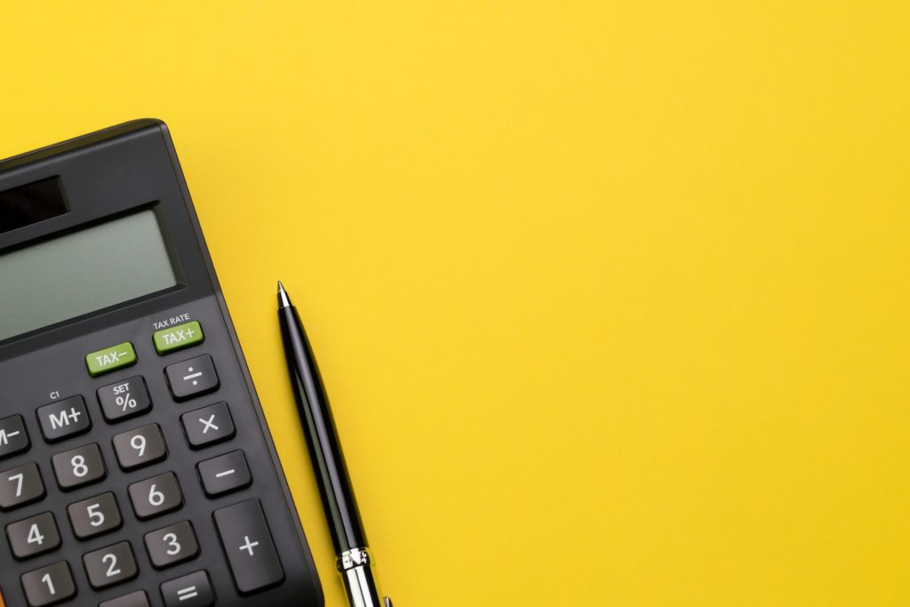 Image of a calculator and a pen on a yellow background
