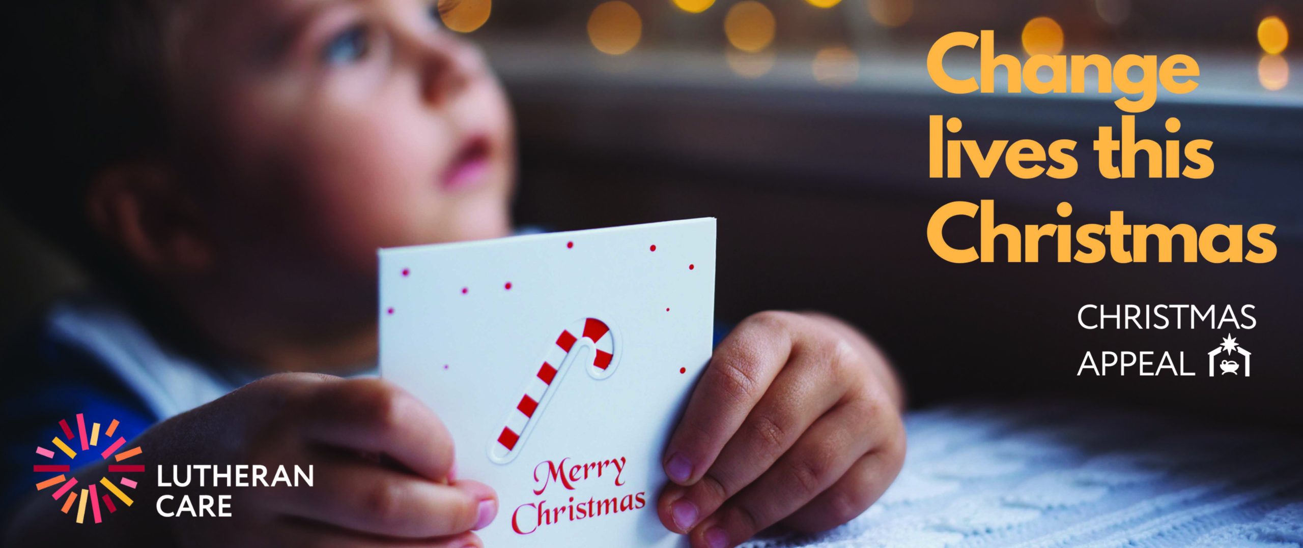 Image of young child holding a card that says Merry Christmas, additional text says change lives this Christmas Christmas Appeal. The Lutheran Care logo appears in the bottom left hand corner