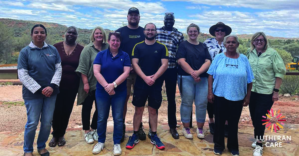 Group photo of the Lutheran Care Northern Territory team outside in Alice Springs. The Lutheran Care logo appears in the bottom right hand corner.