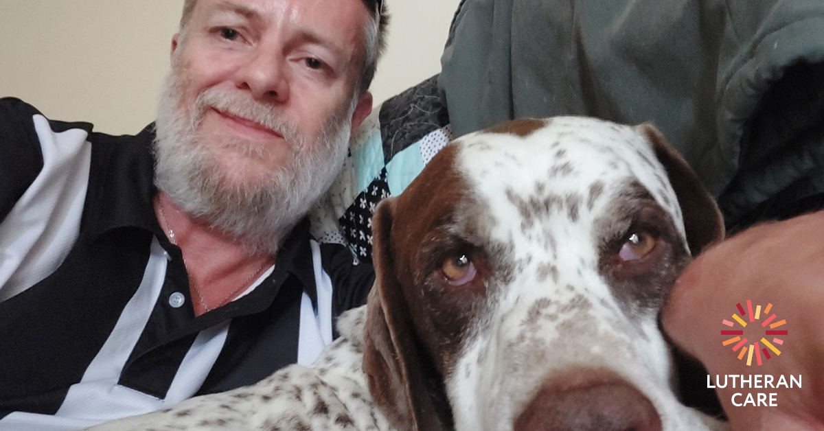 A selfie of Scott and his dog sitting on the couch together. The Lutheran Care logo appears in the bottom right hand corner.