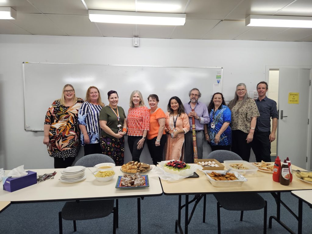 Some of the team from Lutheran Care Blair Athol pose with the cultural foods they brought in to share for Harmony Week. 