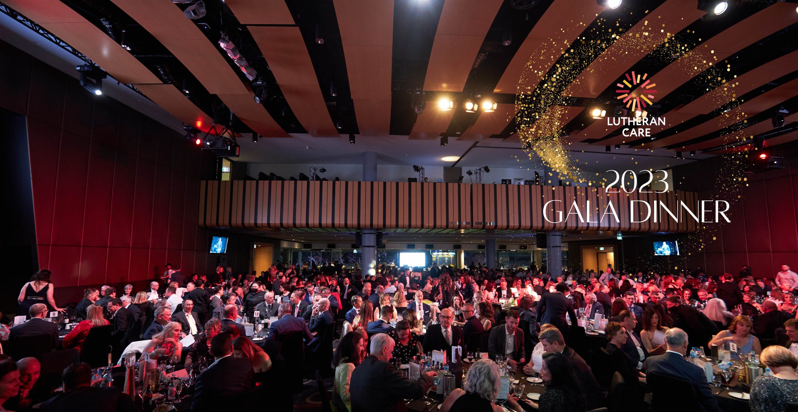Room view of the 2022 Lutheran Care gala dinner with full tables of people talking and eating. Lutheran Care logo appears in the top right hand corner with text underneath that reads 2023 Gala Dinner.