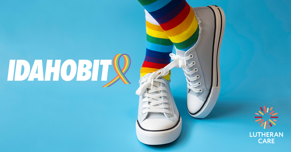 Image of a pair of shoes with one crossed over the other wearing rainbow socks. The IDAHOBIT logo appears on the left hand side and the Lutheran Care logo in the bottom right hand corner.