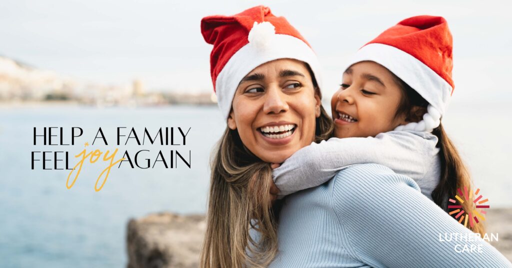 A mother is carrying her young daughter on her back, both are smiling and wearing Santa hats text says help a family feel joy again. The Lutheran Care logo appears in the bottom right hand corner.