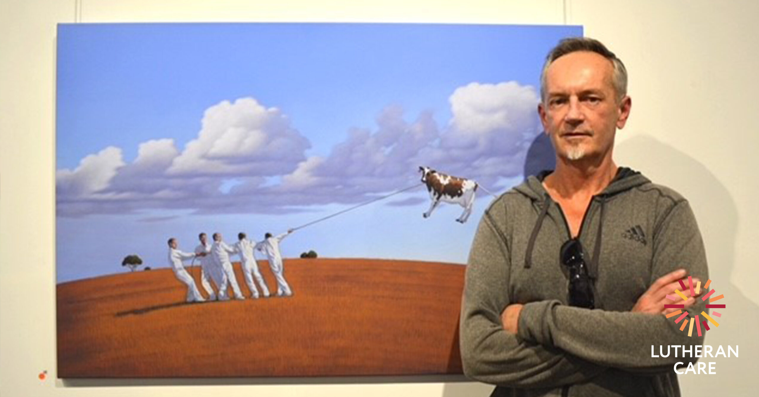 Photo of Andrews Baines in front of his painting. The Lutheran Care logo appears in the bottom right hand corner.