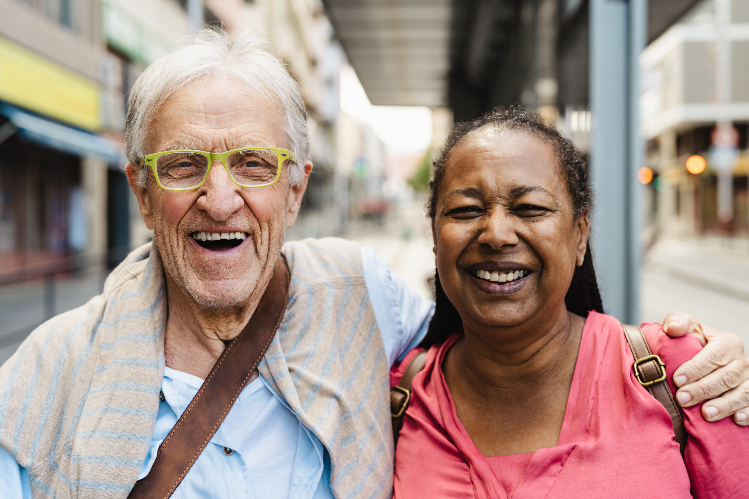 Older man and woman grinning at camera whilst outside