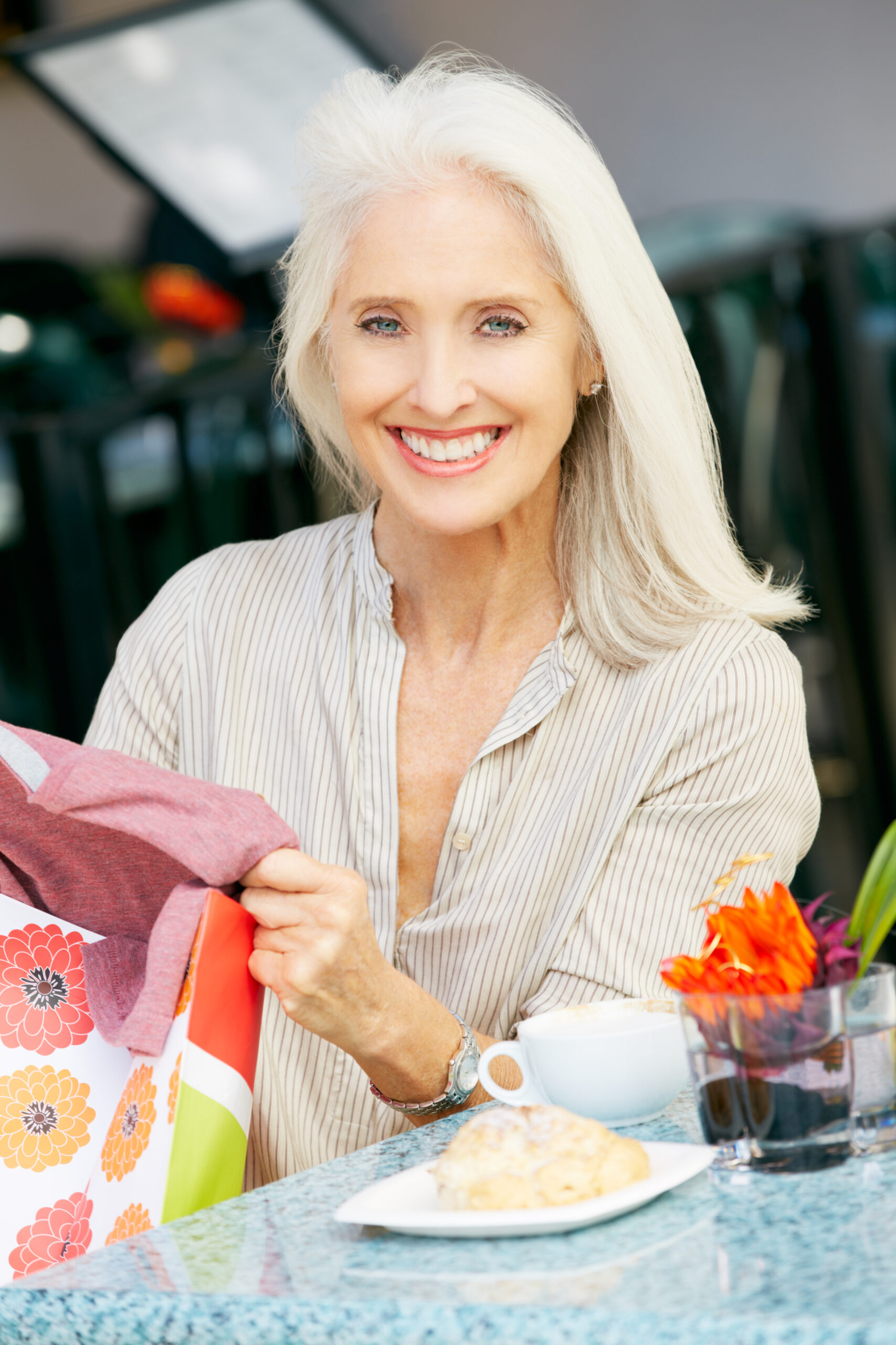 Senior Woman Enjoying Snack At Outdoor Café After Shopping