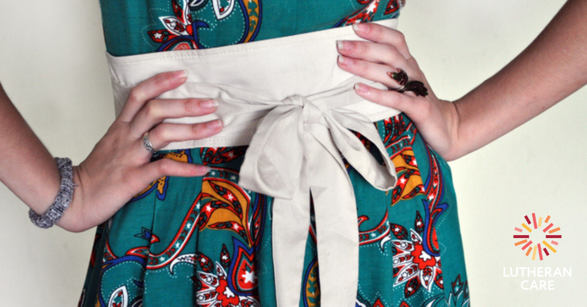 Image shows a person in a green and floral dress with white belt with their hands on their hips. The Lutheran Care logo appears in the bottom right hand corner.