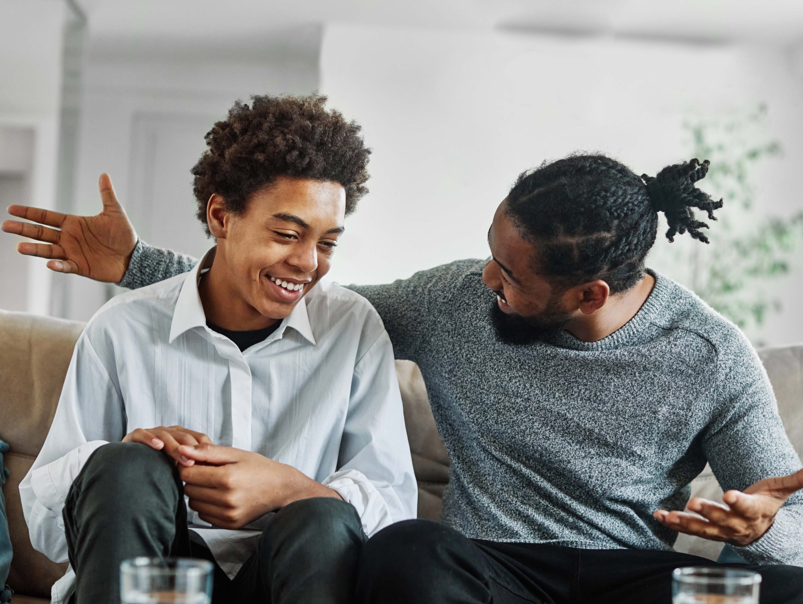 Happy teenage boy son talking to his father at home.