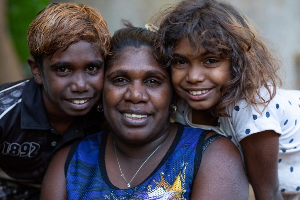 A mother and her two children smile at the camera.