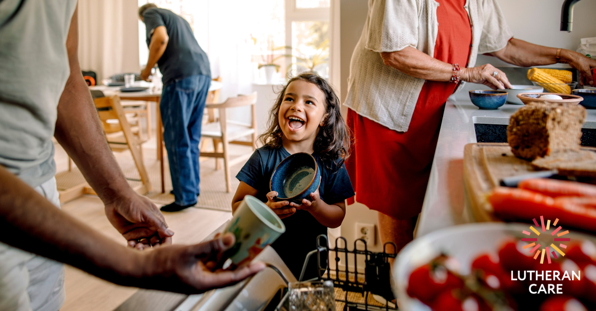 Young happy child in kitchen with family. The Lutheran Care logo appears in the bottom right hand corner.