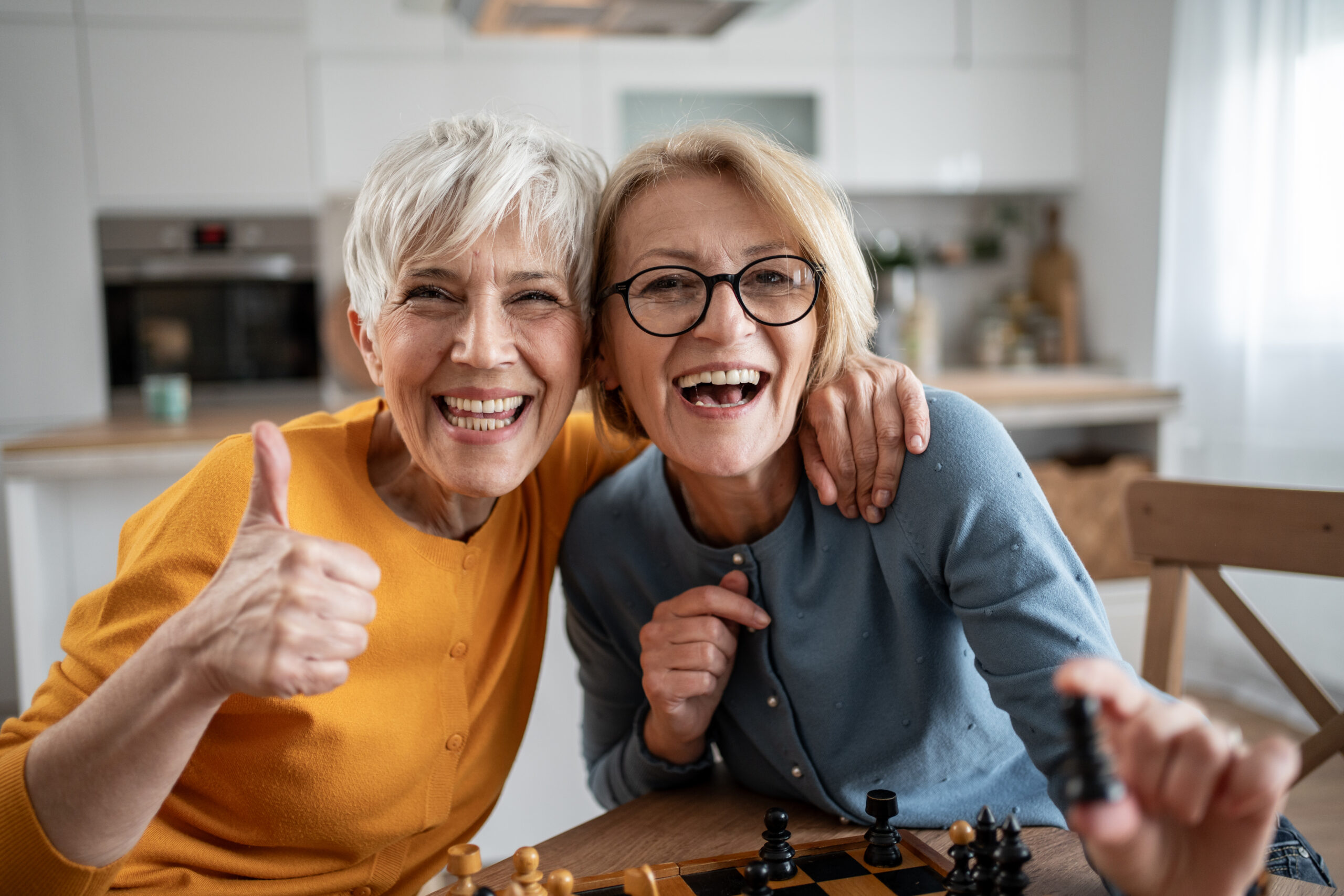 Two senior women playing chess and having fun.
