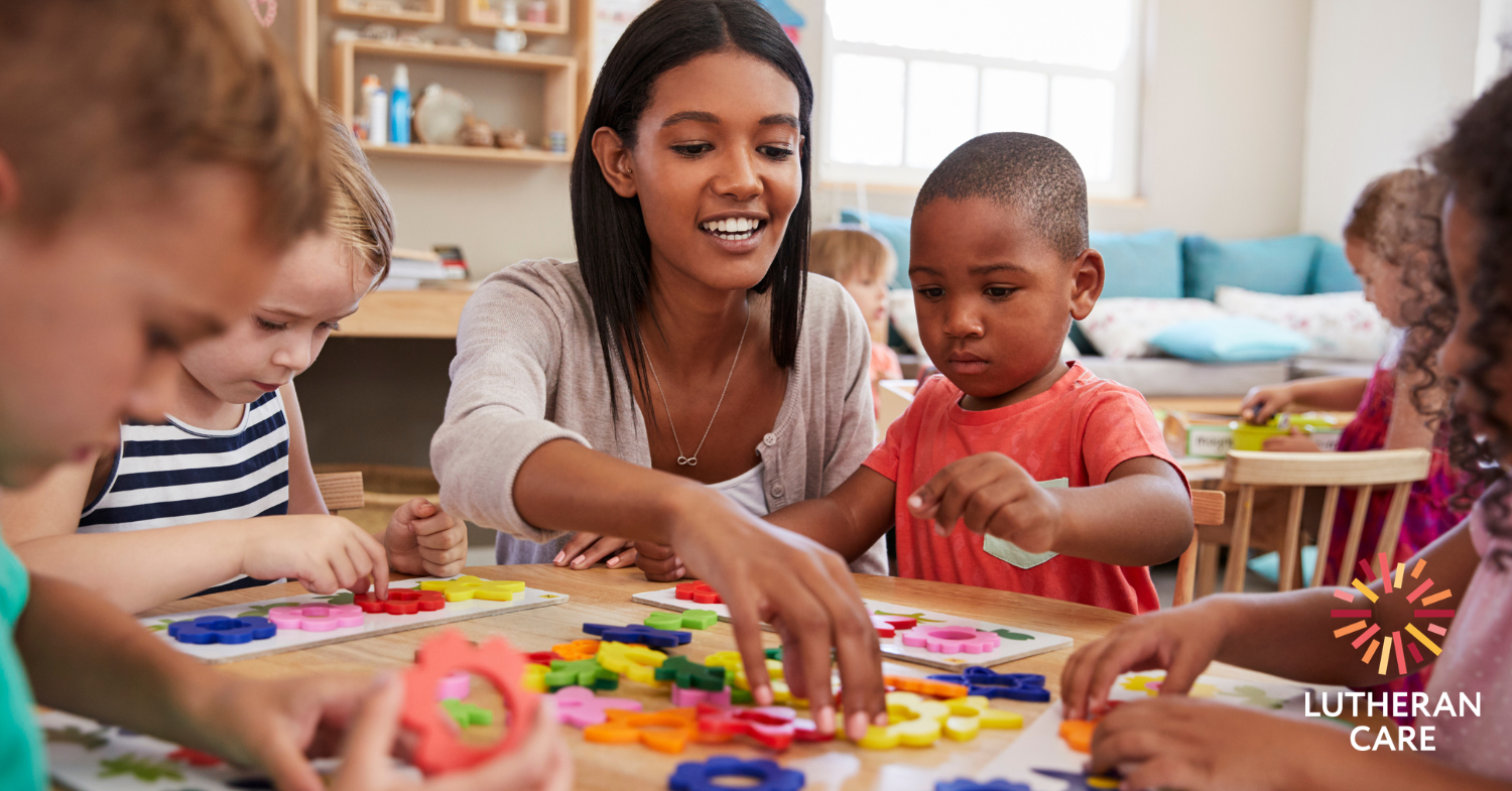 A happy mother and her young son sit at a table completing a puzzle together. The Lutheran Care logo appears in the bottom right hand corner.