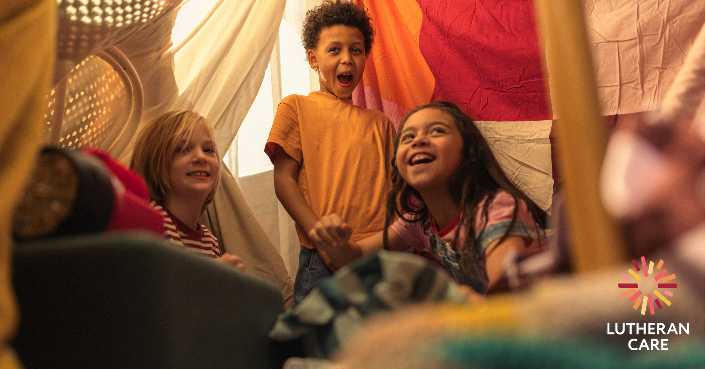 Three children play in a fort. The Lutheran Care logo appears in the right hand corner.